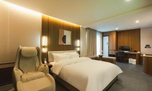 a hotel room with a bed and a chair at Brown Dot Hotel Andong Taehwa in Andong