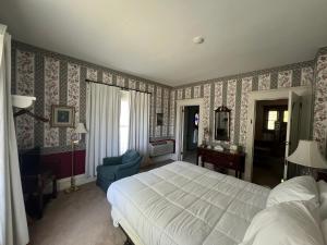 a bedroom with a bed and a chair in it at Strawtown Inn & Events in Pella