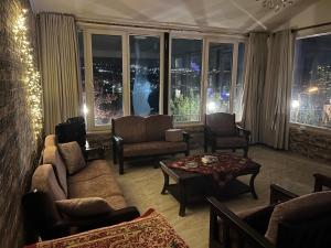 a living room with a couch and a table and windows at Tuscany Villa Jarash in Al Madwar