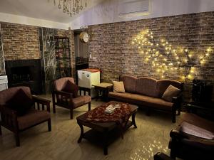 a living room with a couch and chairs and a brick wall at Tuscany Villa Jarash in Al Madwar