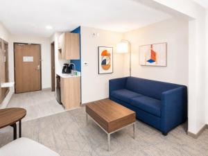 a living room with a blue couch and a kitchen at Holiday Inn Express & Suites Truth or Consequences by IHG - Newly Renovated in Truth or Consequences