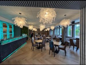 a dining room with tables and chairs and chandeliers at Maritime Łeba in Łeba