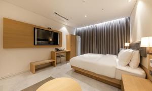 a hotel room with a bed and a flat screen tv at Masan Daisy Hotel in Changwon