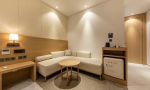 a living room with a white couch and a table at Masan Daisy Hotel in Changwon