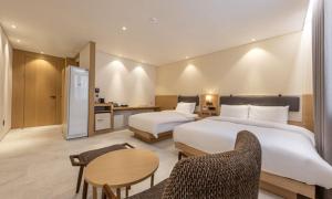 a hotel room with two beds and a table and chairs at Masan Daisy Hotel in Changwon +41 photos