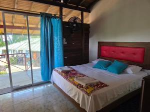 a bedroom with a bed with a red headboard and a window at Ecolodge SOY NUQUI in Nuquí