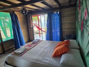 a bed in a room with blue curtains and a window at Ecolodge SOY NUQUI in Nuquí