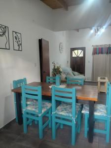 a dining room with a wooden table and blue chairs at Quinta Los Sauces in Nueve de Julio