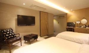 a hotel room with two beds and a chair and a television at Jeonju Mari Hotel in Jeonju