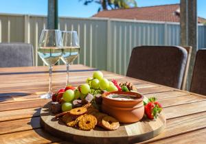 a wooden table with a plate of food and wine glasses at Flinders Hideaway in Shellharbour