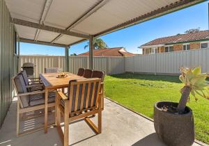 a patio with a table and chairs under a pergola at Flinders Hideaway in Shellharbour