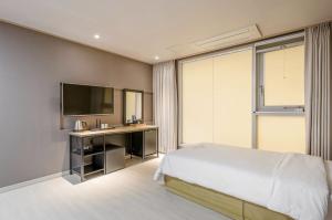 a bedroom with a bed and a desk and a television at Dangjin Hotel IVAN in Dangjin +17 photos