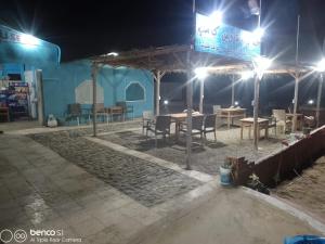 a patio with tables and chairs at night at Hamata House Camp in Abū Ghuşūn +11 photos
