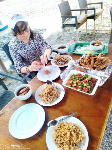 a woman sitting at a table with plates of food at Hamata House Camp in Abū Ghuşūn