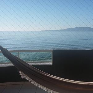 a hammock on a building with a view of the ocean at Apartamento Frente Mar Itapema in Itapema