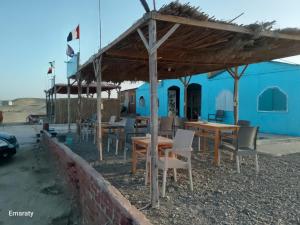 a group of tables and chairs under a blue building at Hamata House Camp in Abū Ghuşūn