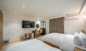 a hotel room with two beds and a desk at Brown Dot Hotel NamGumi in Yangji-mal