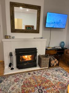a living room with a fireplace and a mirror at WattleJack Cottage in Kingscote