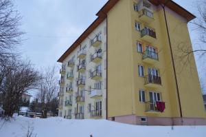 Un bâtiment jaune avec des balcons dans la neige dans l'établissement Apartament Ustrzyki, à Ustrzyki Dolne