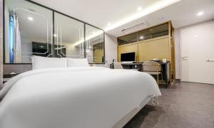 a bedroom with a large white bed and a desk at Paju Geumchon Grache in Paju