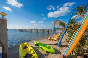 zwei Kajaks und Surfbretter am Strand mit Pier in der Unterkunft Carpe Diem in Stuart