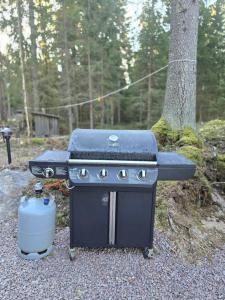a black barbecue grill with a cooler on the ground at Seaside cottage with private beach & wood-fired sauna in Vörå, Finland in Oravais