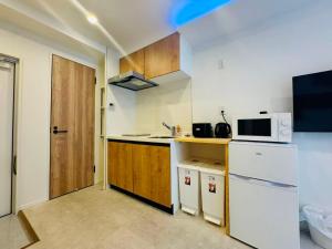 a small kitchen with a white refrigerator and a microwave at Simplex-Iriya in Tokyo
