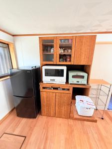 a kitchen with a black refrigerator and a microwave at ゲストハウスめぐみ in Iizuka