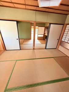 an empty room with two doors on the floor at ゲストハウスめぐみ in Iizuka