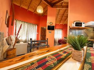 a living room with orange walls and a wooden table at Cabañas La Matera Apart in Los Reartes