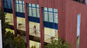a woman standing on a balcony in front of a building at Geoje Erion Pet-Friendly Pension in Geoje +1 photo