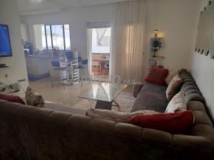 a living room with a brown couch and a kitchen at mona in Sidi Rahal
