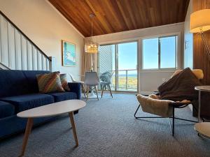 a living room with a blue couch and a table at Oceanfront Studio with Loft - amazing views! in Qualicum Beach