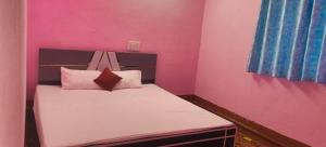 a small bedroom with a bed with pink walls at Hotel Sunrise inn in Nārdiganj