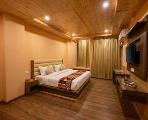 a bedroom with a bed and a flat screen tv at Mist Valley By Zenia in Fagu