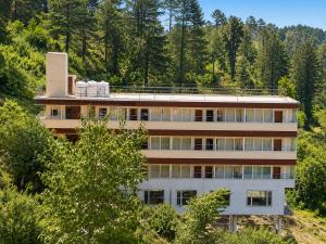 a building on the side of a hill with trees at Mist Valley By Zenia in Fagu