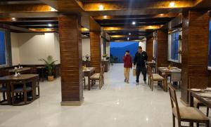 two people walking through a restaurant with tables and chairs at Mist Valley By Zenia in Fagu +16 photos
