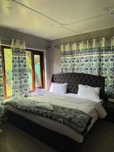 a bedroom with a large bed with blue and white curtains at Zabaish Riverside Cottage in Pahalgām