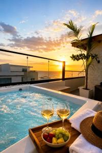 two glasses of wine and a bowl of fruit next to a swimming pool at Luxurious Ocean View Penthouse in Boca Chica