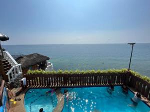 a swimming pool with the ocean in the background at Cliff Cabanas by Hiverooms in Catmon
