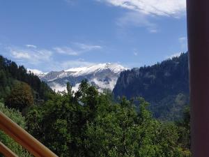 a view of a snow covered mountain from a balcony at Nirvana Stays and Cafe in Manāli