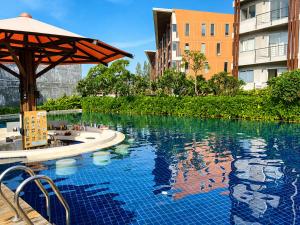 a swimming pool with an umbrella and some buildings at Cozy 1-Bedroom Apartment Near Fisherman's Village in Nathon Bay