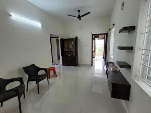 a living room with chairs and a ceiling fan at Sunstar in Coimbatore
