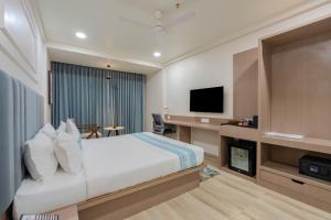 a hotel room with a bed and a tv at Hotel TGR in Ankleshwar