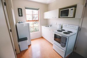 a small kitchen with a stove and a microwave at Addington Stadium Motel in Christchurch