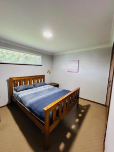 a bedroom with a wooden bed with blue sheets at Stouty's at Hat Head - No Sheets or Towels Provided in Hat Head