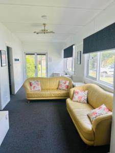 a living room with two yellow couches and two windows at Bonnydoon at Hat Head - 5 Oak Street in Hat Head
