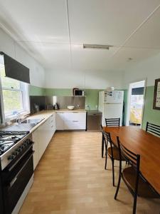 a kitchen with a wooden table and a kitchen with a stove and a dining room at Bonnydoon at Hat Head - 5 Oak Street in Hat Head