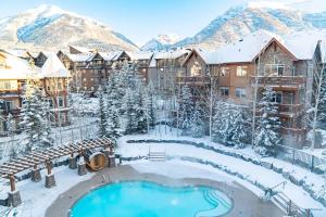 a resort with a swimming pool in the snow at The Eagle Suite at Stoneridge Mountain Resort in Canmore