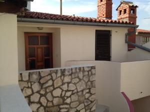 Casa blanca con pared de piedra y puerta en Apartment Iva, en Fažana